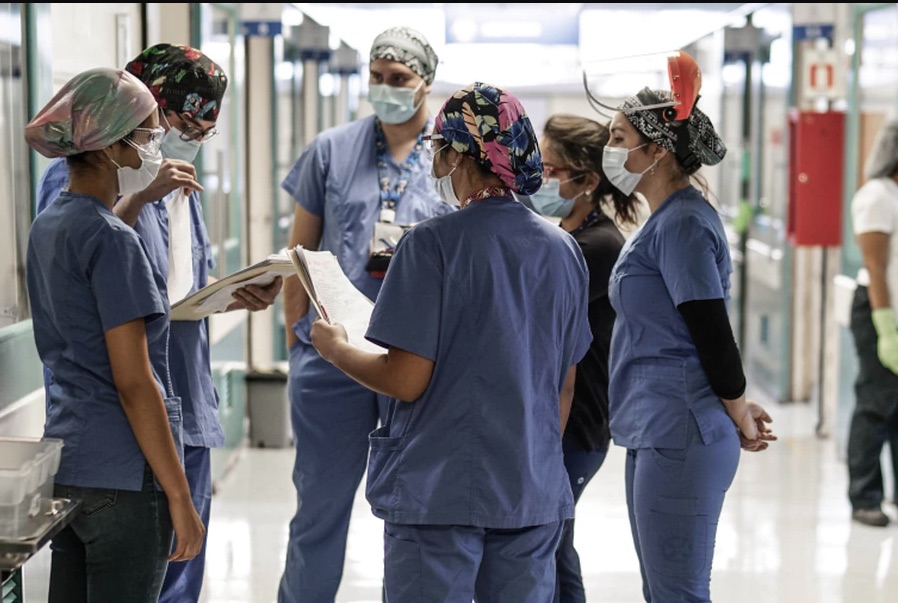 Equipo clínico coordinando entre turnos en el pasillo de un hospital